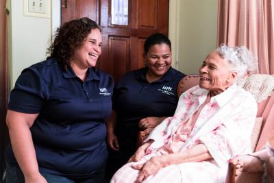 Two standing volunteers laugh with a sitting client