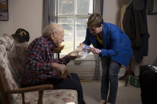 A volunteer gives a meal to a Meals on Wheels client