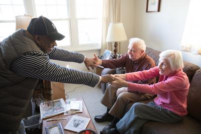 A volunteer reaches over to embrace the hands of two seated clients