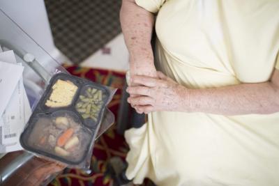 A packaged meal next to the arms of a client