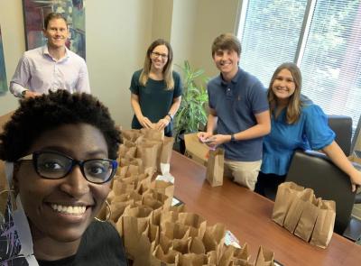 Four volunteers smile as they bag supplemental food for clients