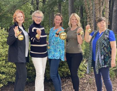 Board members smile holding golden disco balls